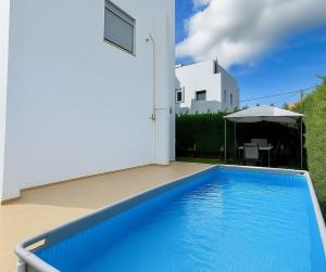 a blue swimming pool in front of a white house at Casa Verde Pastida in Pastida