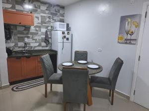 a kitchen with a table and chairs and a refrigerator at Flat da Belly 904-A Hidro Piscina Praia in São Vicente