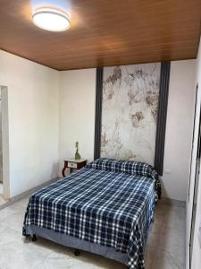 a bedroom with a bed with a plaid blanket at Hostal Casa Hope in Rivas