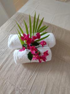 a bouquet of pink flowers sitting on top of towels at Logement chic au style tropical contemporain in Îlet à Christophe +7 photos