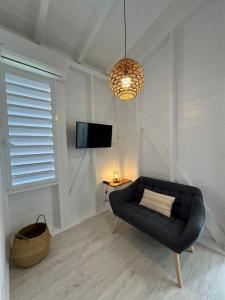 a living room with a black couch and a tv at Logement chic au style tropical contemporain in Îlet à Christophe