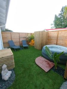 a backyard with a hot tub and chairs on grass at Logement chic au style tropical contemporain in Îlet à Christophe