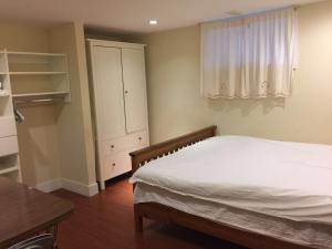 a bedroom with a bed and a cabinet and a table at Dunbar Home in Vancouver