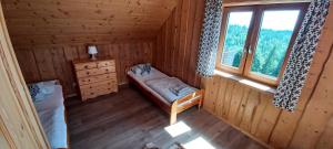 a room with a bed and a window in a log cabin at Domek na Przełęczy in Ochotnica Górna