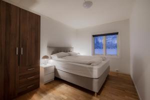 a white bedroom with a bed and a window at Fauske Central Apartment - Cozy & Walkable in Fauske