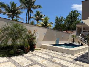 a swimming pool in the backyard of a house with palm trees at Recanto da Ivete in São Sebastião