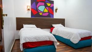 a room with two beds and a painting on the wall at Résidence Meublée Jihane in Laayoune