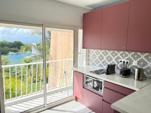 a kitchen with purple cabinets and a balcony with a view at Rêve Marina studio tout confort avec citerne et piscine Gosier in Pointe-à-Pitre