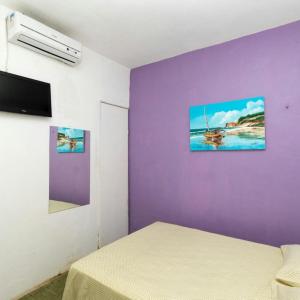 a room with purple walls and a bed and a tv at Pousada Maresia in Fortaleza