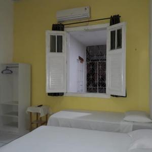 a bedroom with a window with white shutters and a bed at Pousada Maresia in Fortaleza +4 photos