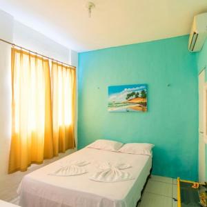 a bedroom with a bed with a blue wall at Pousada Maresia in Fortaleza