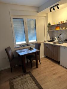a kitchen with a table and chairs and two windows at Happy moments Studio Kraljevo in Kraljevo +18 photos