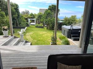 a porch with a view of a backyard with a grill at Pacific Ocean Breezes in Whangaparaoa +6 photos