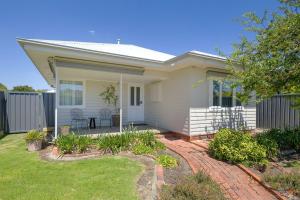 a white house with a patio and a fence at Cute Cummings St Cottage in Wodonga