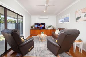 a living room with two chairs and a tv at Cute Cummings St Cottage in Wodonga