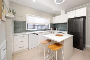 a kitchen with white cabinets and a black refrigerator at Cute Cummings St Cottage in Wodonga