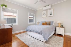 a bedroom with a bed and a dresser and two windows at Cute Cummings St Cottage in Wodonga