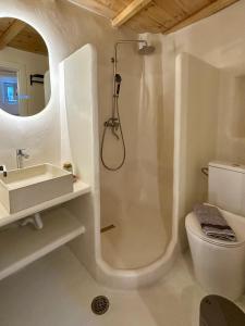 a white bathroom with a shower and a sink at Lythi Kythnos in Kithnos