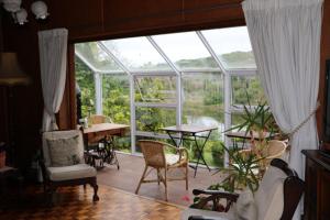 a conservatory with a table and chairs and a large window at Forword's River Lodge in East London