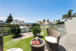 a patio with chairs and a table on a balcony at Longbeach Ocean Paradise in Mount Maunganui