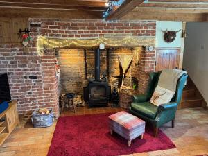 a living room with a brick fireplace and a green chair at Cosy Flint Cottage in Thurston