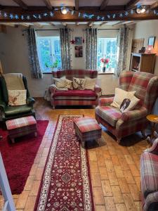 a living room with couches and a rug at Cosy Flint Cottage in Thurston