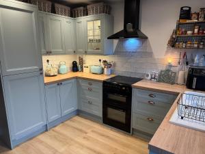 a kitchen with blue cabinets and a stove top oven at Cosy Flint Cottage in Thurston