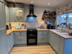 a kitchen with white cabinets and a black stove at Cosy Flint Cottage in Thurston +28 photos