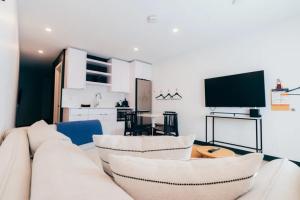 a living room with a white couch and a tv at Gravity Haus Revelstoke in Revelstoke