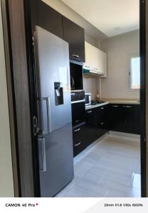 a kitchen with a white refrigerator and black cabinets at Serenity in Dakan