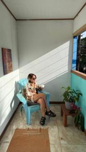 a woman sitting on a blue chair in a room at Soul Rebel Hostel in Puerto Viejo