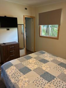 a bedroom with a bed and a dresser and a television at Cabaña de Lujo Independiente in Frutillar