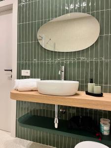a bathroom with a sink and a green tiled wall at Angilè Rooms in Agrigento +9 photos