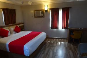 a hotel room with a bed and a desk and window at Vienna Suites in Owerri