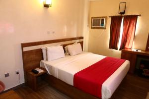 a bedroom with a large bed with a red blanket at Vienna Suites in Owerri