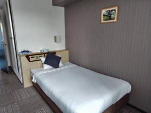 a bedroom with a large white bed with a blue pillow at パーク琴芝 in Ube