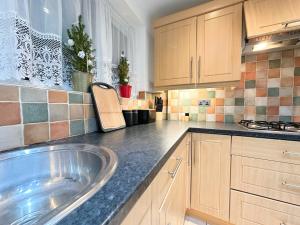 a kitchen with a sink and wooden cabinets at Luton Airport Accomodation in Luton
