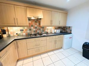 a kitchen with wooden cabinets and a white refrigerator at Luton Airport Accomodation in Luton