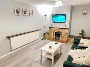 a living room with a fireplace and a flat screen tv at Luton Airport Accomodation in Luton
