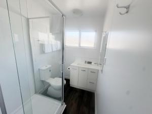 a white bathroom with a toilet and a glass shower at Midway Pacifica Lodge in Lower Hutt