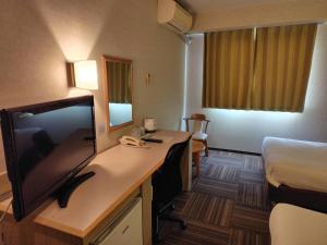 a hotel room with a desk with a television and a bed at パーク琴芝 in Ube +16 photos
