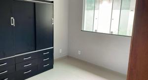 a bedroom with a black dresser and a window at Casa com piscina in Araruama