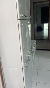 a white refrigerator in a kitchen with white tiles at Casa com piscina in Araruama