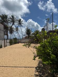 a sandy beach with palm trees in the background at Barra Adventure Pousada in Mataraca