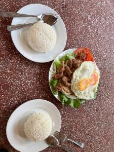 two plates of food with rice on a table at El Ling guesthouse in Kep