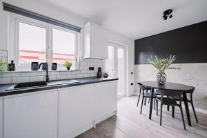 a kitchen with white cabinets and a black table at ComfySleep ApartHOUSE in Glasgow