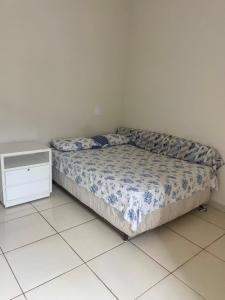 a small bed in a room with a white floor at Casa Aconchegante Alfenas in Alfenas