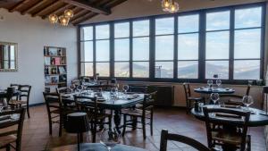 ein Restaurant mit Tischen und Stühlen und großen Fenstern in der Unterkunft Fortebraccio Hotel & Spa in Montone