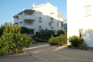 a large white building with bushes in front of it at Apartment Sun in Novalja