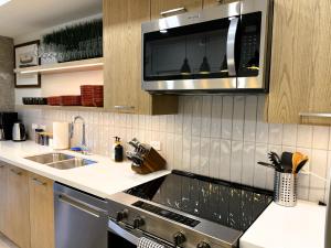 a kitchen with a sink and a microwave at Black Bears Den, Heated Pool, Hot Tub, AC, brand new unit! in Canmore